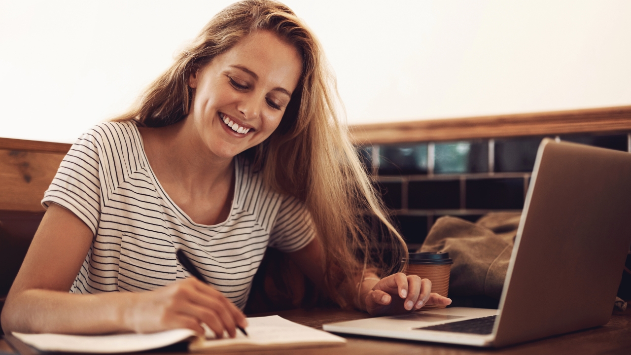 Studentkinja računa troškove studiranja uz laptop i beleške